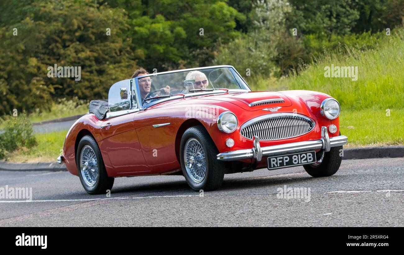 Stony Stratford, Royaume-Uni - 4 juin 2023: 1964 rouge AUSTIN HEALEY 3000 voiture classique voyageant sur une route de campagne anglaise. Banque D'Images