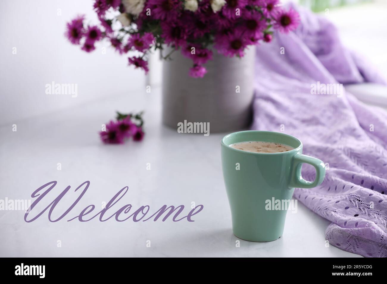 Carte de bienvenue. Tasse de café aromatique, belles fleurs et tissu violet sur table blanche Banque D'Images