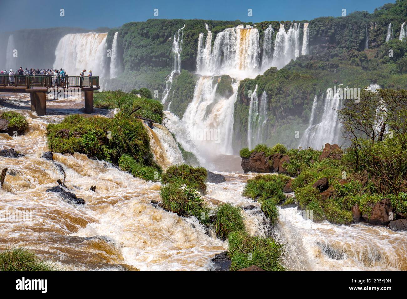 Vue sur les spectaculaires chutes d'Iguazu avec plate-forme pour visiteurs et ciel bleu Banque D'Images