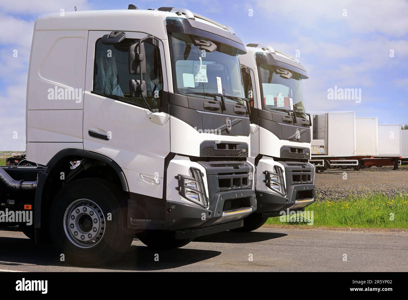 Deux nouveaux camions poids lourd Volvo FMX blancs pour la construction stationnés sur une cour en plein soleil d'été. Forssa, Finlande. 10 juin 2022. Banque D'Images
