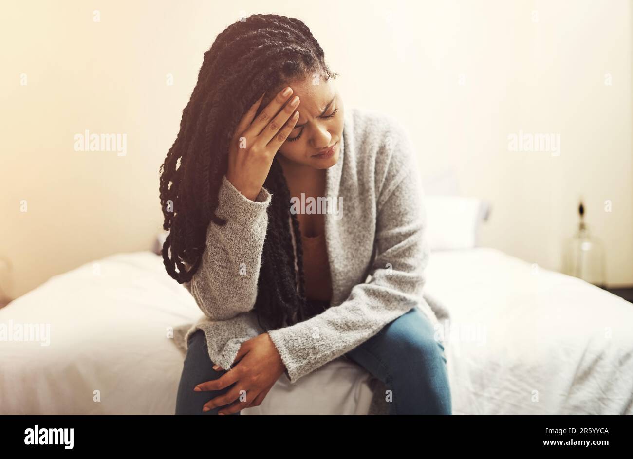 Je suis tellement fatigué de me sentir ainsi. une jeune femme qui a l'air dépressive assis sur son lit. Banque D'Images