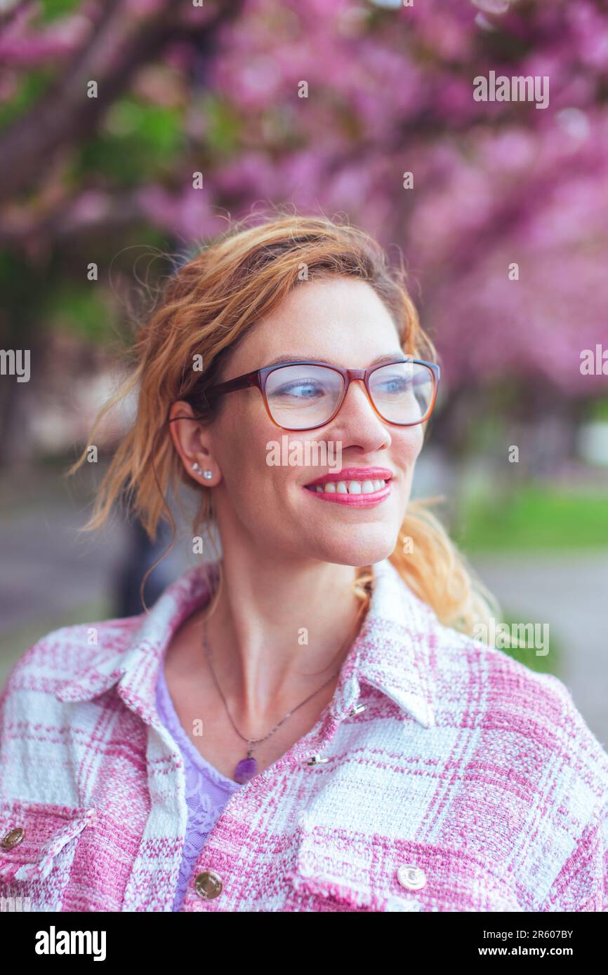 Bonne jeune femme en lunettes de vue en regardant loin dans le parc au printemps Banque D'Images