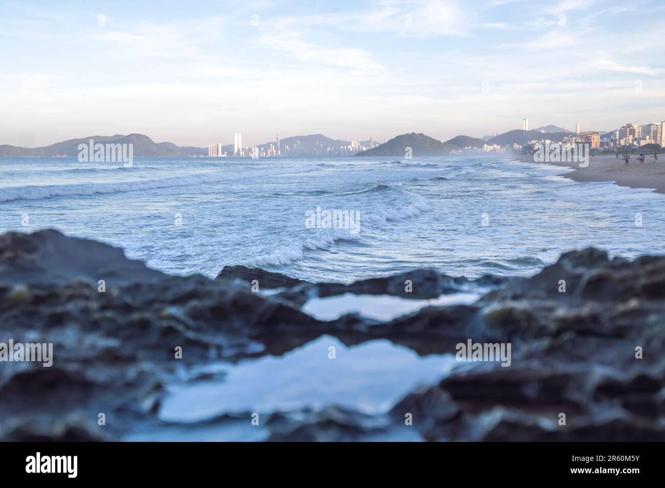 Pierres humides par les vagues de la mer et de la ville de balneario camboriu-sc brésil en arrière-plan, concept de plage et de tourisme. Banque D'Images