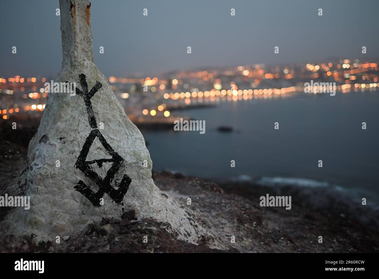 Une grande formation rocheuse avec texte inscrit sur sa surface se trouve sur la côte d'un océan Banque D'Images
