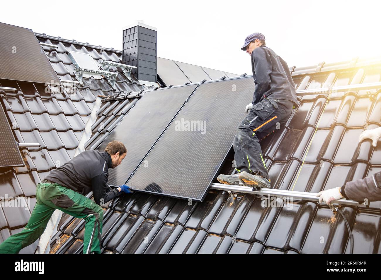 Ouvriers installant des panneaux solaires sur le toit d'une maison Banque D'Images