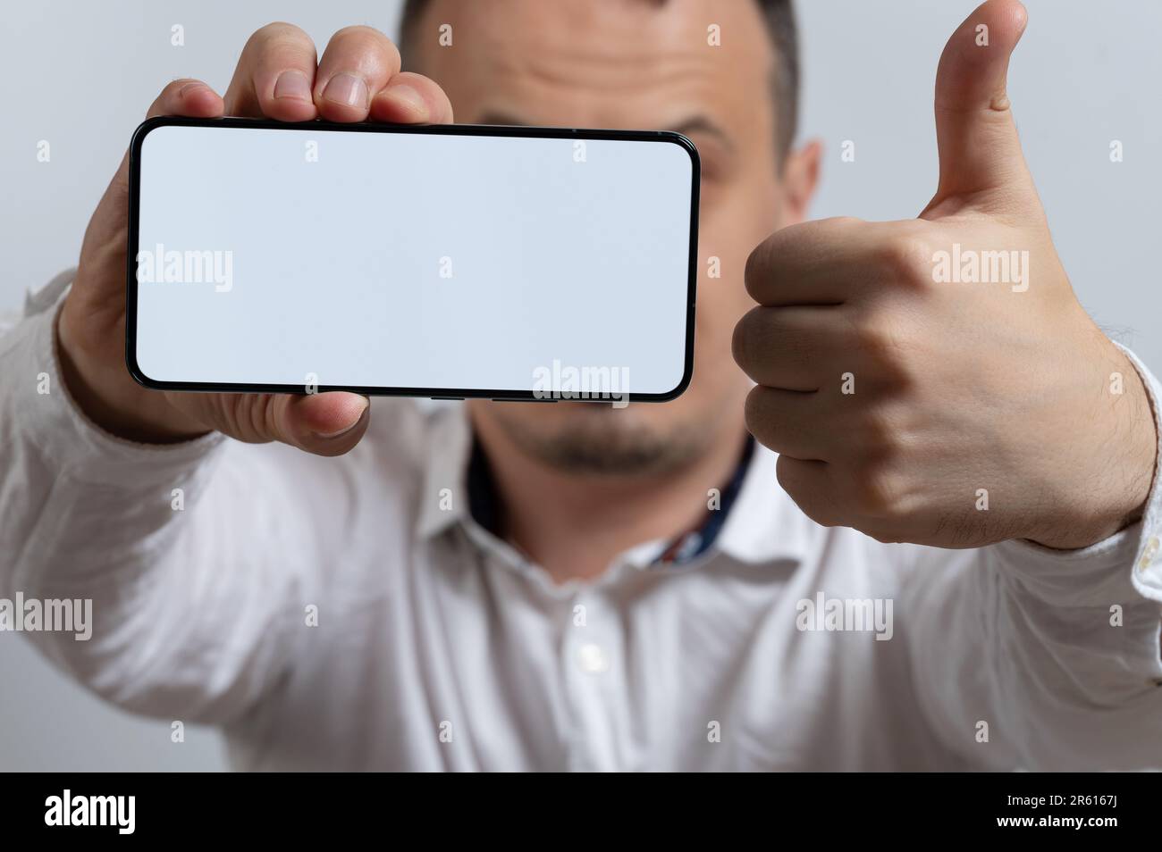 L'homme donne le pouce au service en ligne et tient le smartphone à portée de main Banque D'Images