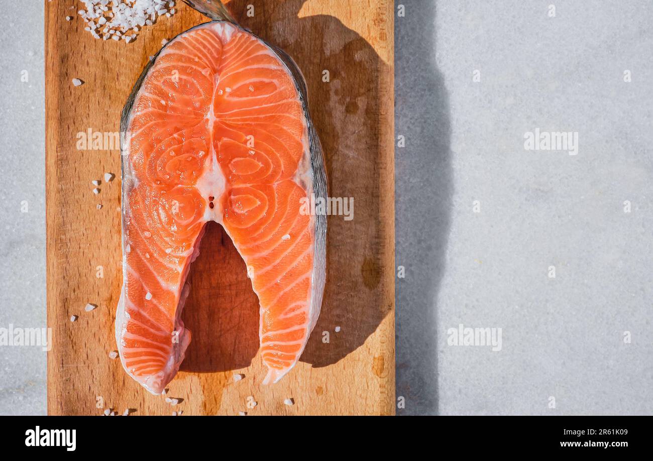 Steak de saumon sur planche à découper en bois, idée de soupe de poisson finlandaise ou fond pour la recette de steak de poisson. Keto alimentation bio à la table, soleil naturel Banque D'Images