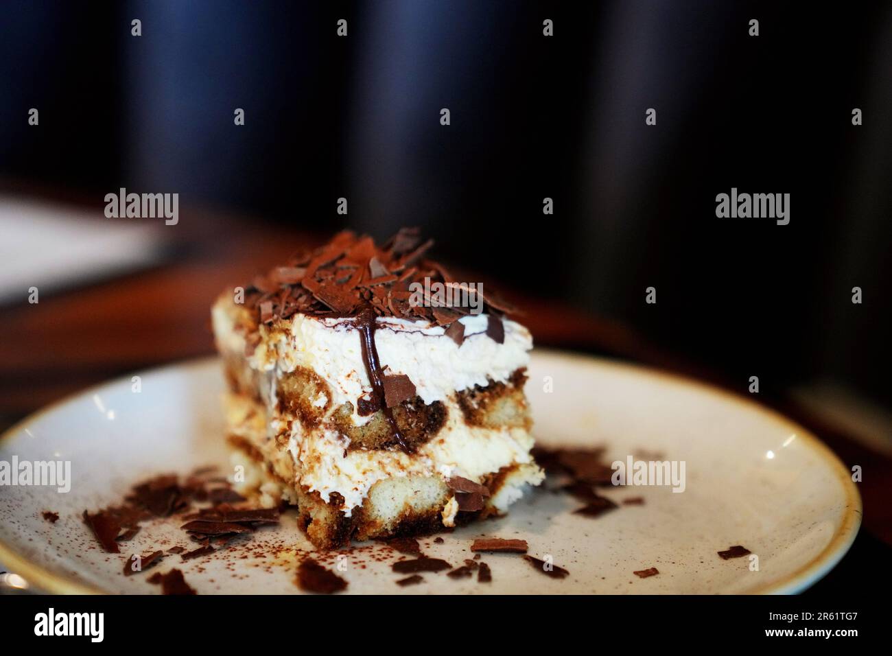 Une assiette blanche avec un dessert italien traditionnel Tiramisu, délicatement recouverte de copeaux de chocolat pour plus de texture et de saveur Banque D'Images