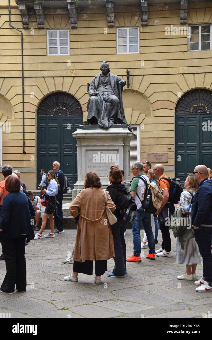 Touristes regardant la statue de Francesco Carrara, politicien italien, lors d'une visite guidée de la ville historique de Lucques, Toscane, Italie, avril 2023 Banque D'Images