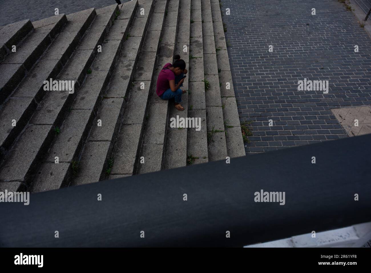 Bilbao, Espagne - 03 août 2022: Jeune femme chat au téléphone assis dans les escaliers extérieur bâtiment travail de bureau Banque D'Images
