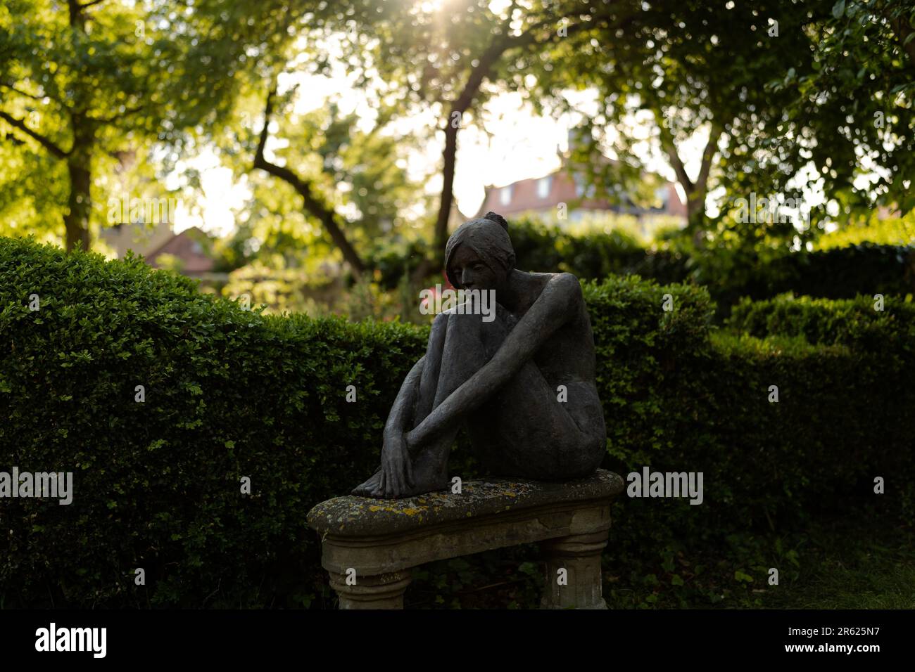 Une sculpture en pierre représentant une femme assise, ses bras se sont croisés sur ses jambes Banque D'Images