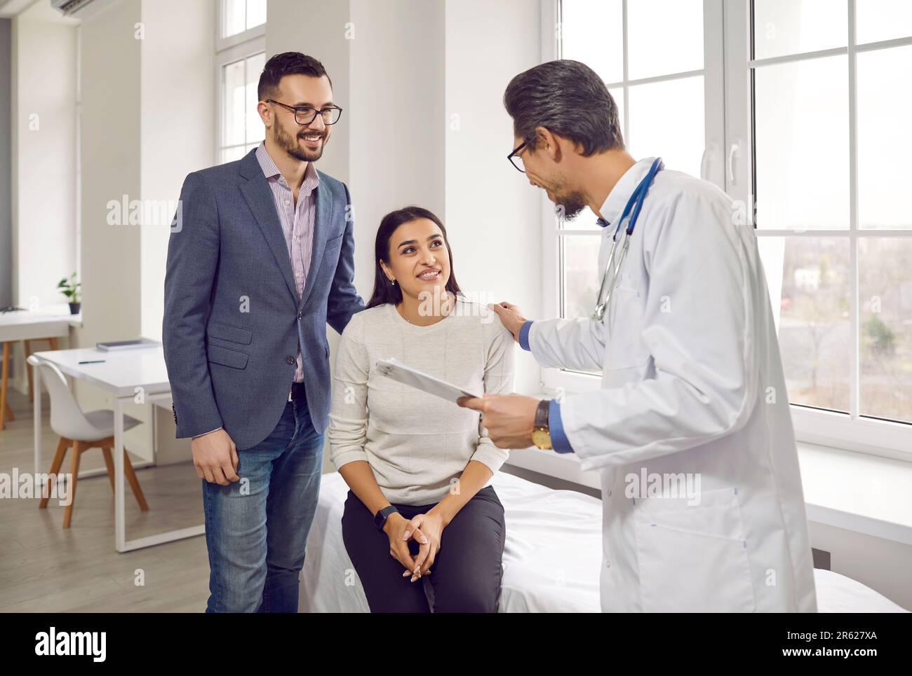 Jeune couple marié écouter attentivement un sympathique gynécologue