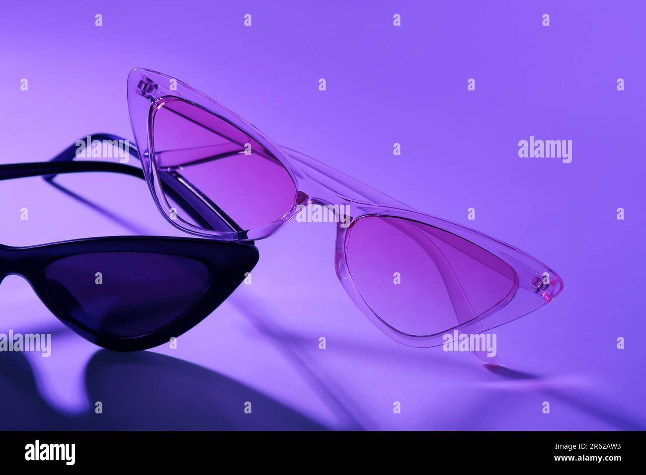 Différentes lunettes de soleil élégantes sur fond violet Banque D'Images