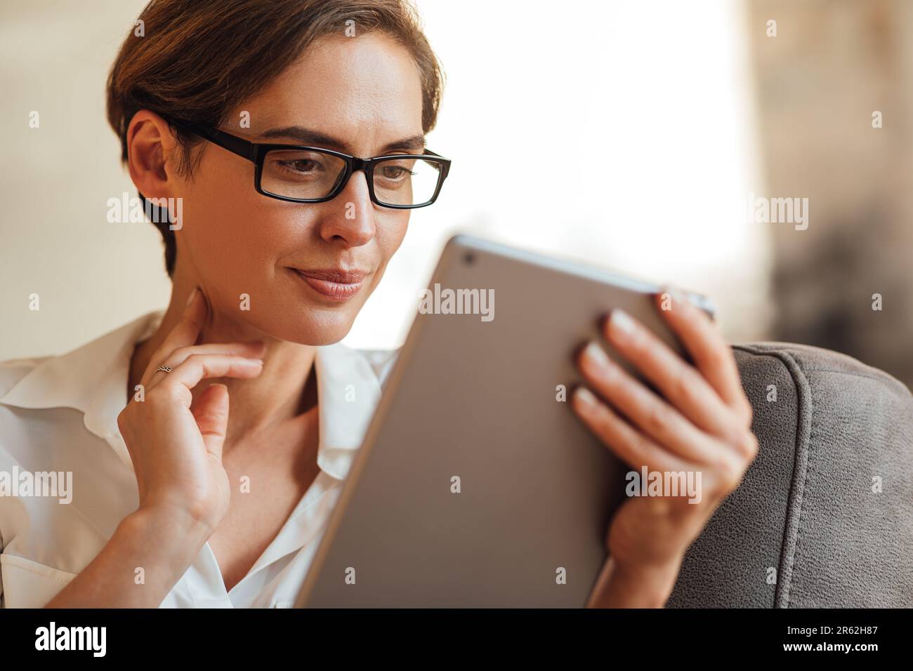 Gros plan d'une femme d'affaires en lunettes à l'aide d'une tablette numérique. Portrait d'une femme avec une tablette numérique. Banque D'Images