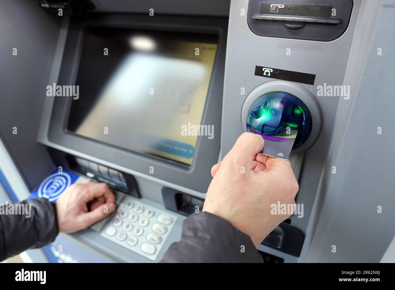 Un homme effectuant une transaction avec une carte de crédit à un guichet automatique ATM Banque D'Images