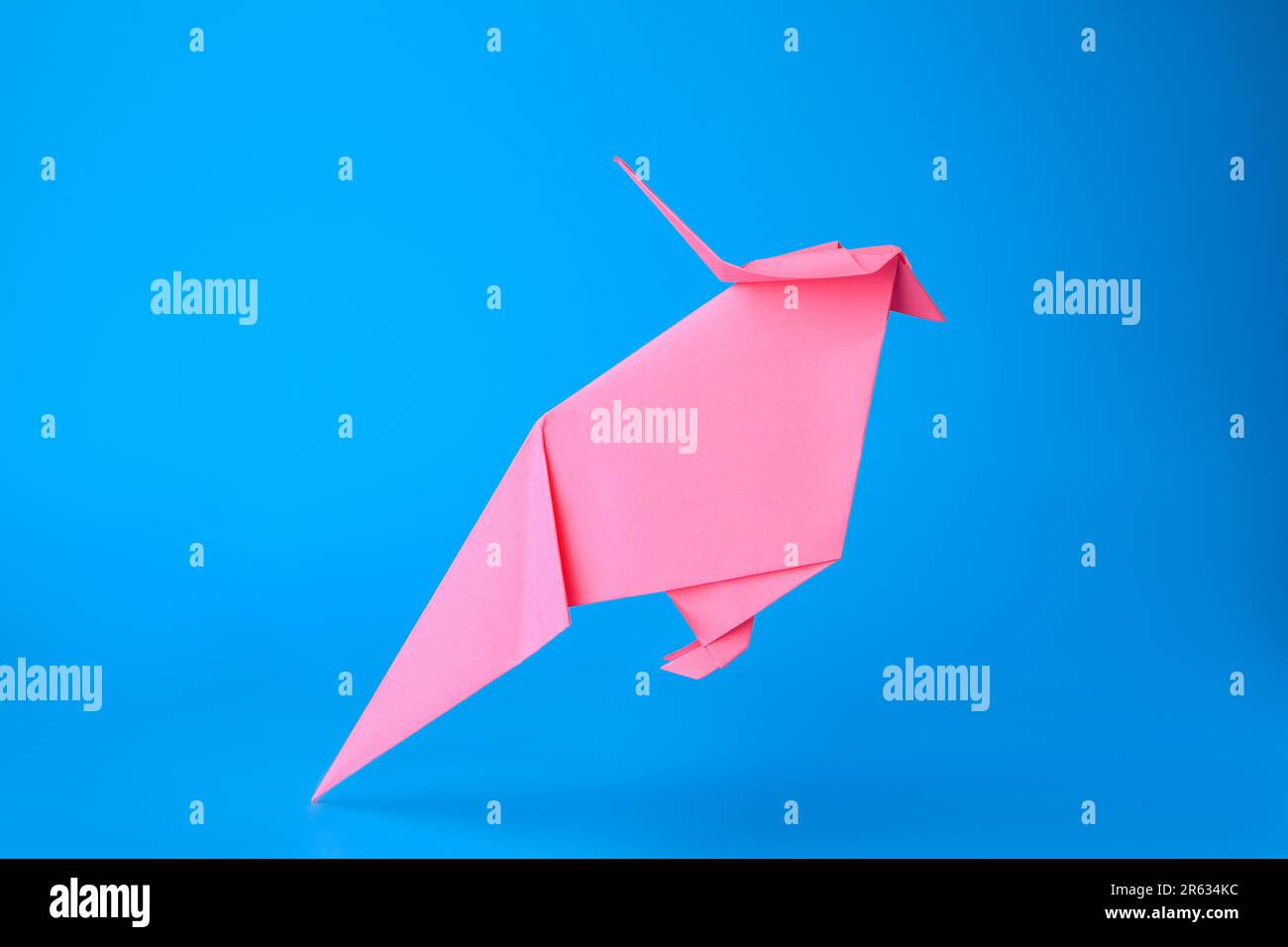 Art origami Perroquet en papier rose fait à la main sur fond bleu clair Banque D'Images