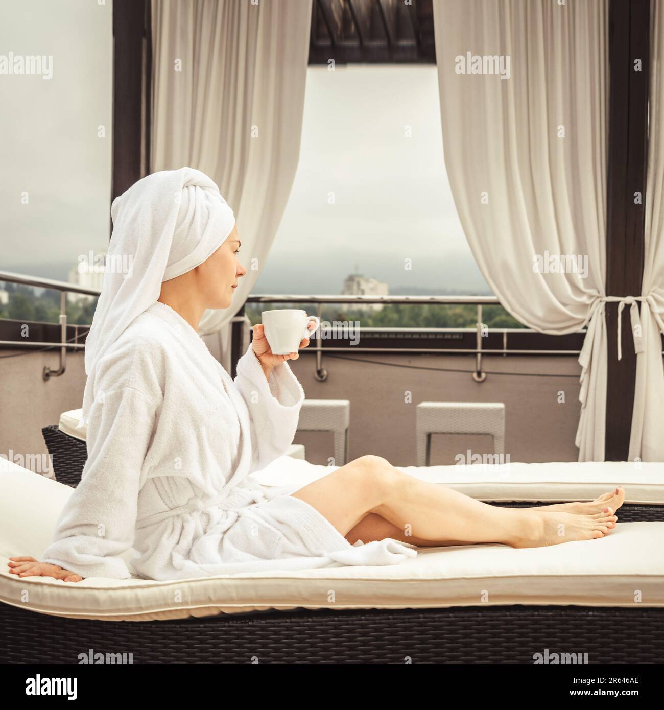 Femme en peignoir blanc et serviette sur le canapé et détente avec thé sur  le toit de l'hôtel Photo Stock - Alamy
