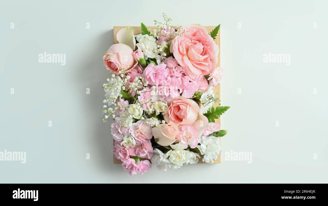 Caisse en bois pleine de couleurs pastel fleurs avec rose rose et carnation sur fond blanc Banque D'Images