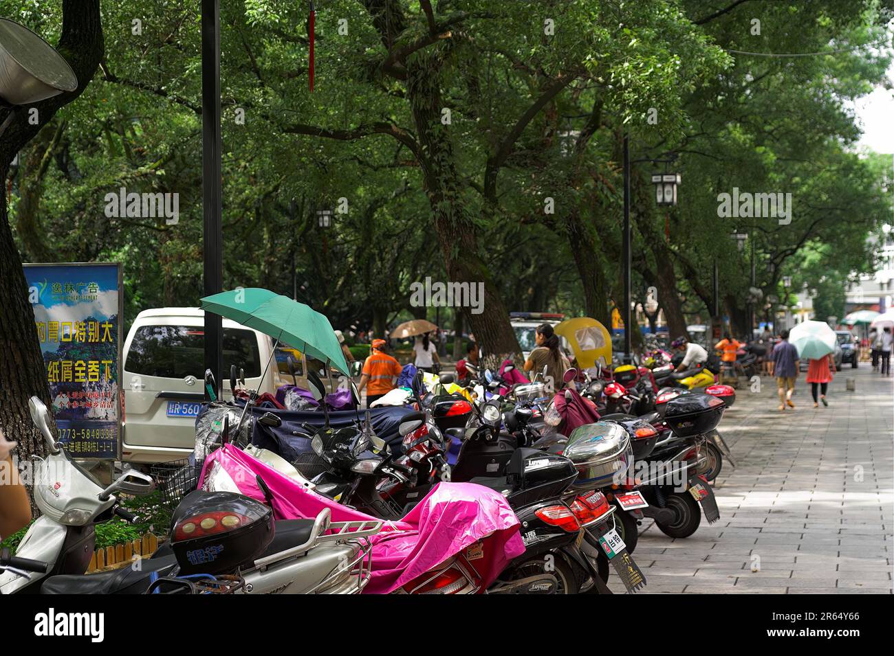 龙胜镇 (龙胜县) 中國 Longsheng Chine ; scooters garés sur un large trottoir dans la ville chinoise ; Auf dem Bürgersteig in einer chinesischen Stadt geparkte Motorroller Banque D'Images