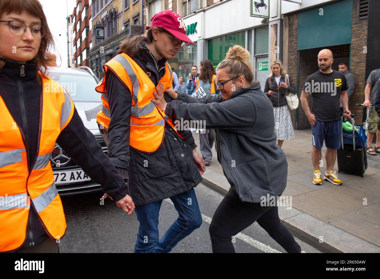 Londres, Angleterre, Royaume-Uni 7 juin 2023 Angry Woman, Et d'autres membres du public se confrontent à de jeunes manifestants Just Stop Oil qui se promêtent lentement à Hammersmith, une femme qui n'était pas une conductrice attaque une jeune militante qui la raflant sur le trottoir, tandis que d'autres hommes poussent et traînent de jeunes filles. Banque D'Images