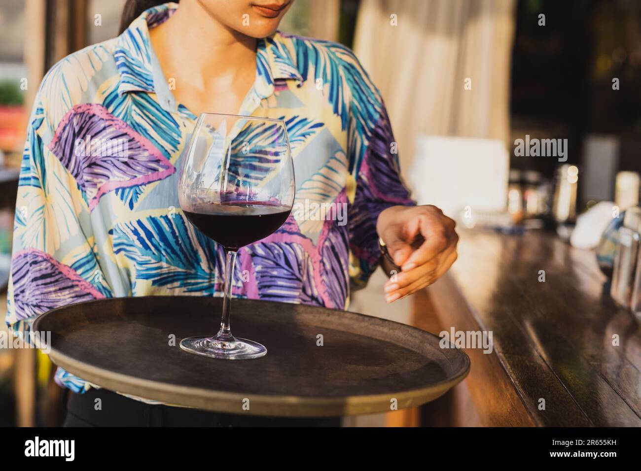 Serveuse servant un verre de vin rouge sur un plateau Banque D'Images
