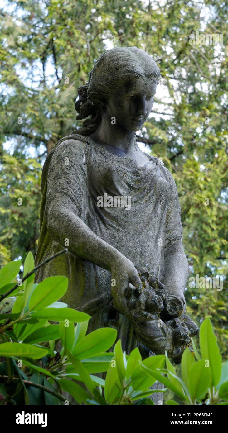 Sculpture d'une belle femme dans un cimetière. Elle tient une couronne dans ses mains. Banque D'Images