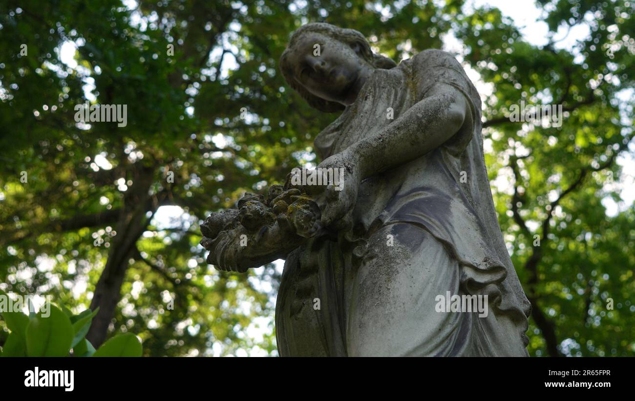 Sculpture d'une belle femme dans un cimetière. Elle tient une couronne dans ses mains. Banque D'Images