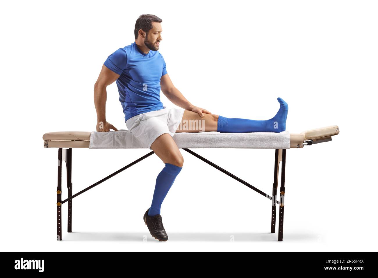 Athlète sportif assis sur une table de thérapie isolée sur fond blanc Banque D'Images
