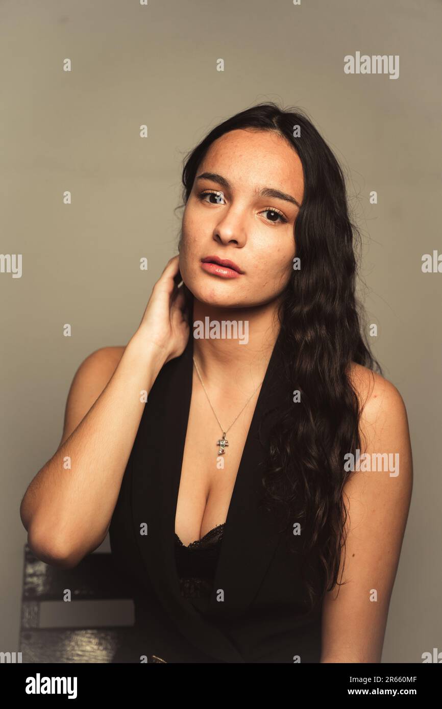 Une jeune femme aux cheveux foncés portant une robe noire debout avec une posture détendue Banque D'Images