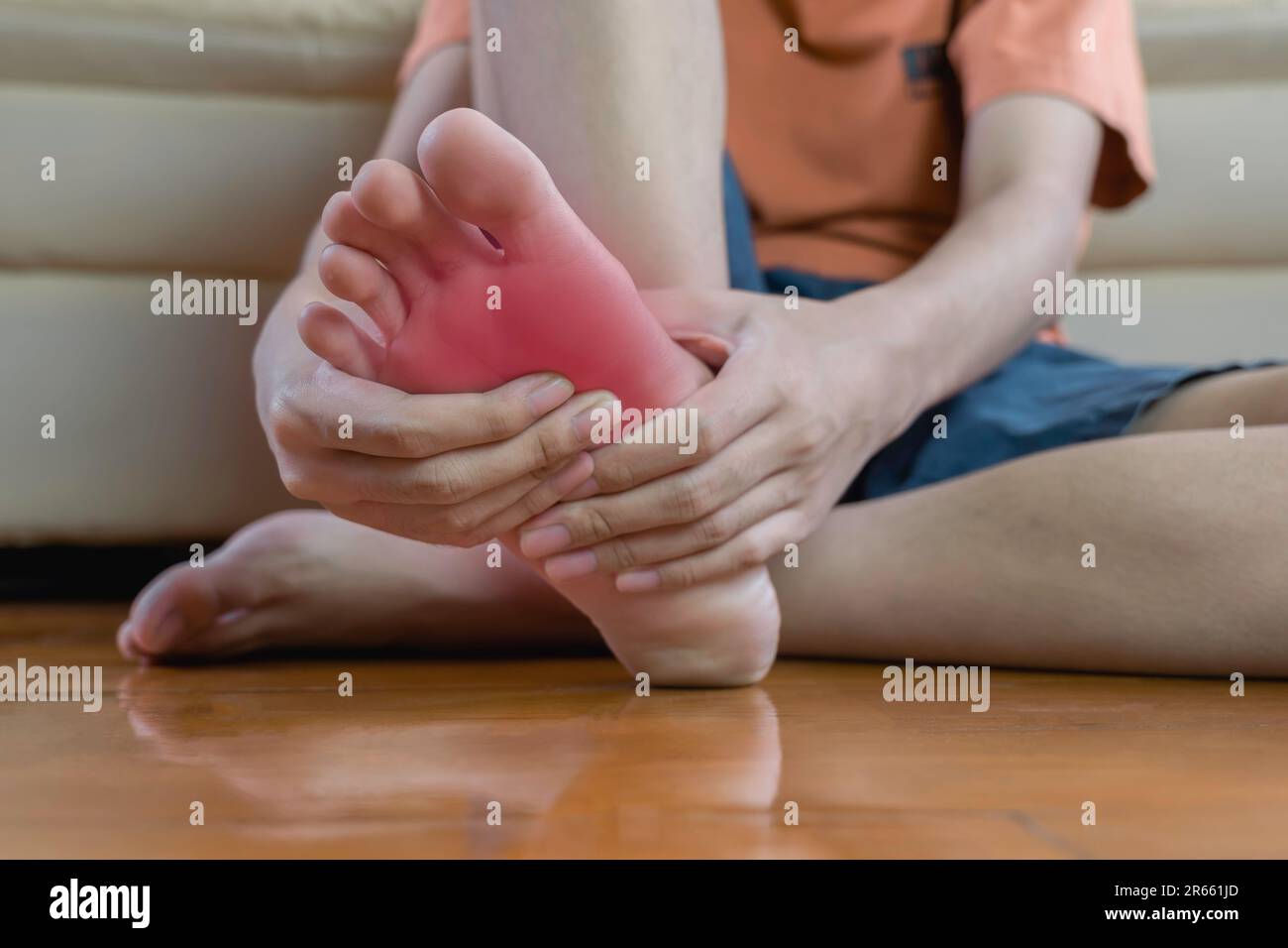 Le jeune homme tient les mains de son pied et souffre de douleurs au pied. Massage des mains pour adolescents détendez-vous avec un muscle assis sur un canapé. Soins de santé et podiatrie moi Banque D'Images