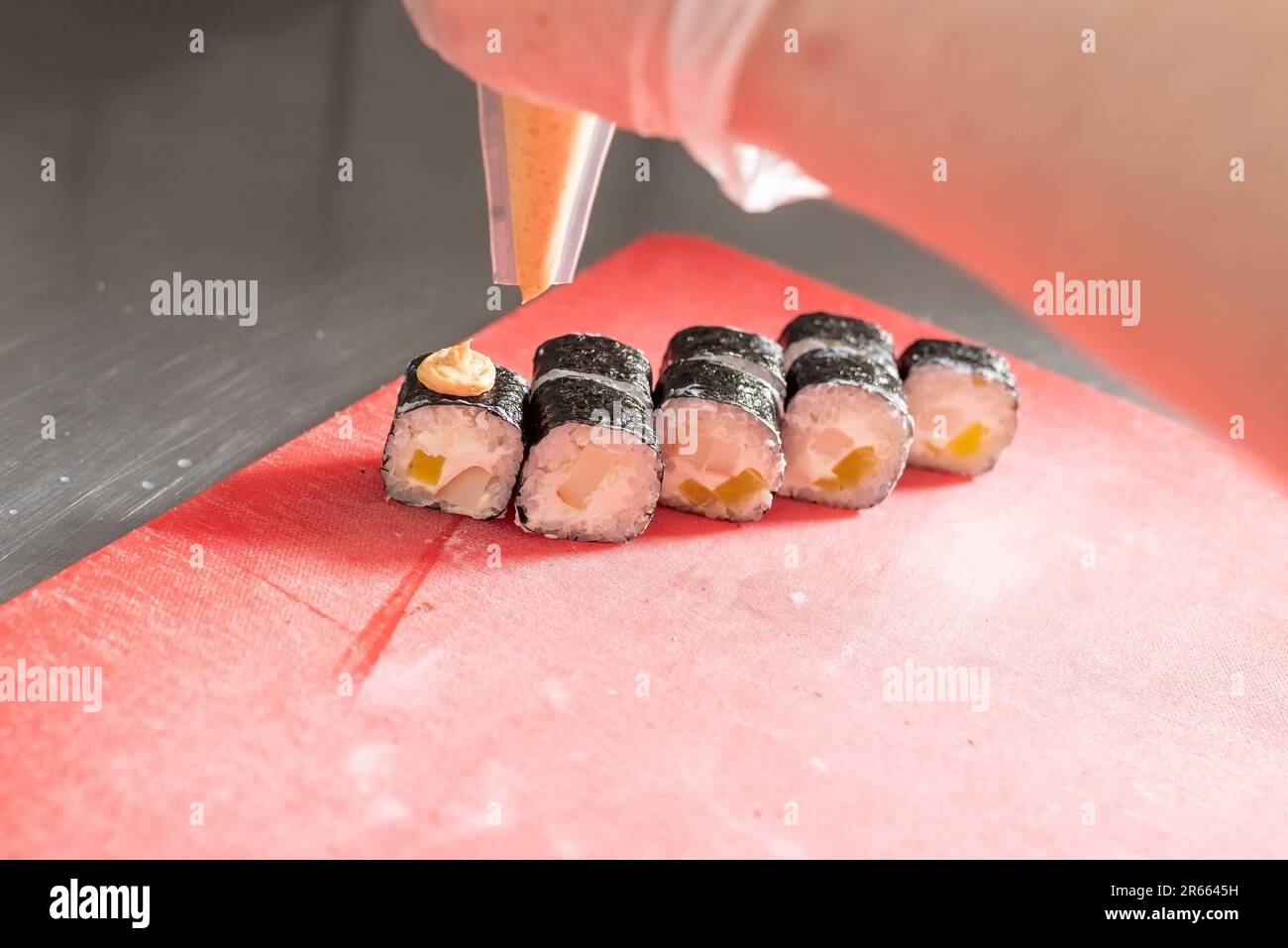 Application de la sauce épicée sur les sushis au fromage et au daikon. Photo de haute qualité Banque D'Images