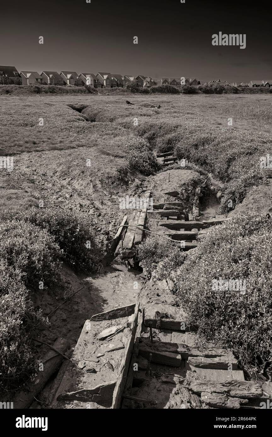 Restes de vieux bateaux sur l'estuaire de la rivière Wyre avec de nouveaux logements en arrière-plan Banque D'Images