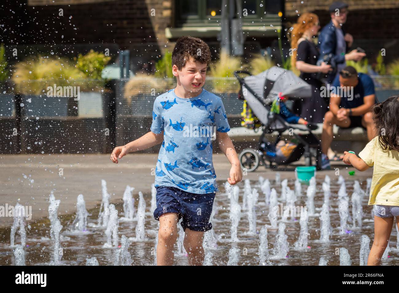 Londres, Royaume-Uni - 21 juin 2023 - vague de chaleur à Londres, les enfants jouent avec de l'eau pour se rafraîchir aux fontaines de Granary Square à Kings Cross Banque D'Images