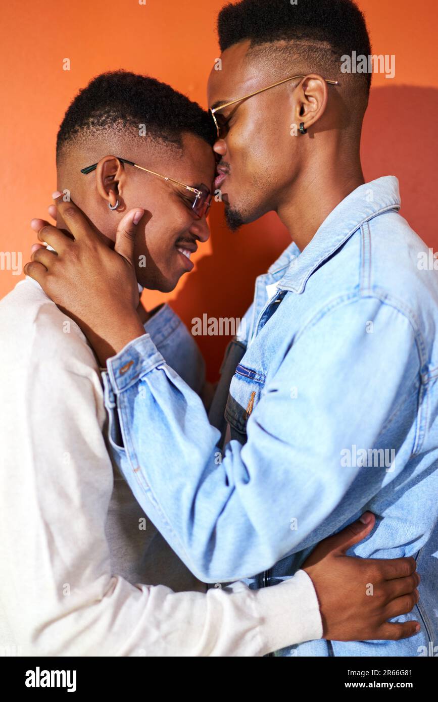 Portrait affectueux jeune gay couple masculin en lunettes de soleil embrassant Banque D'Images