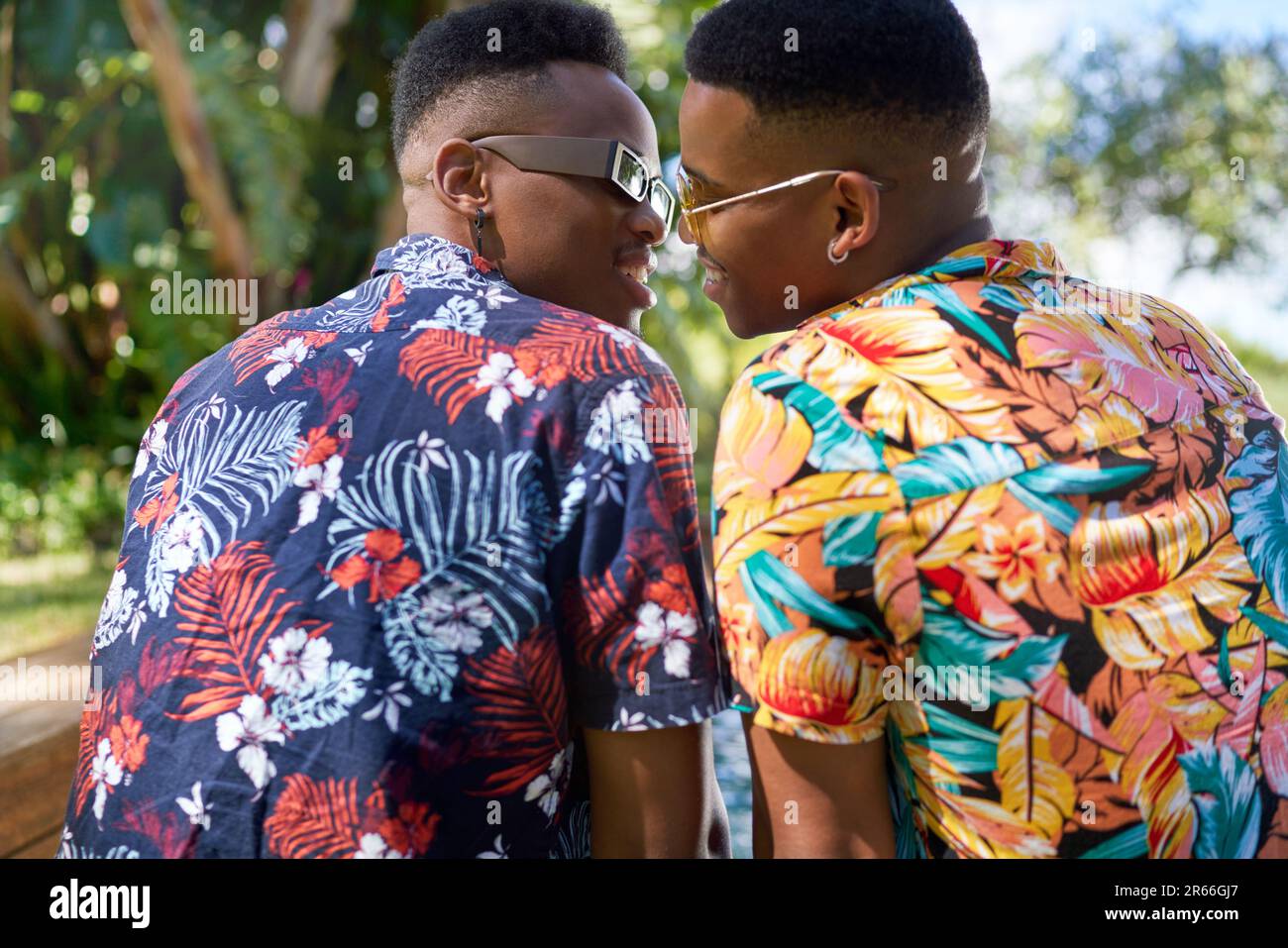 Un couple gay affectueux en chemises hawaïennes embrassant Banque D'Images