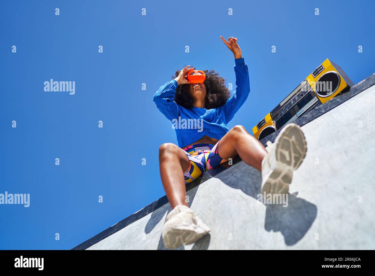 Jeune femme avec un caisson de perche utilisant le viseur contre le ciel bleu Banque D'Images