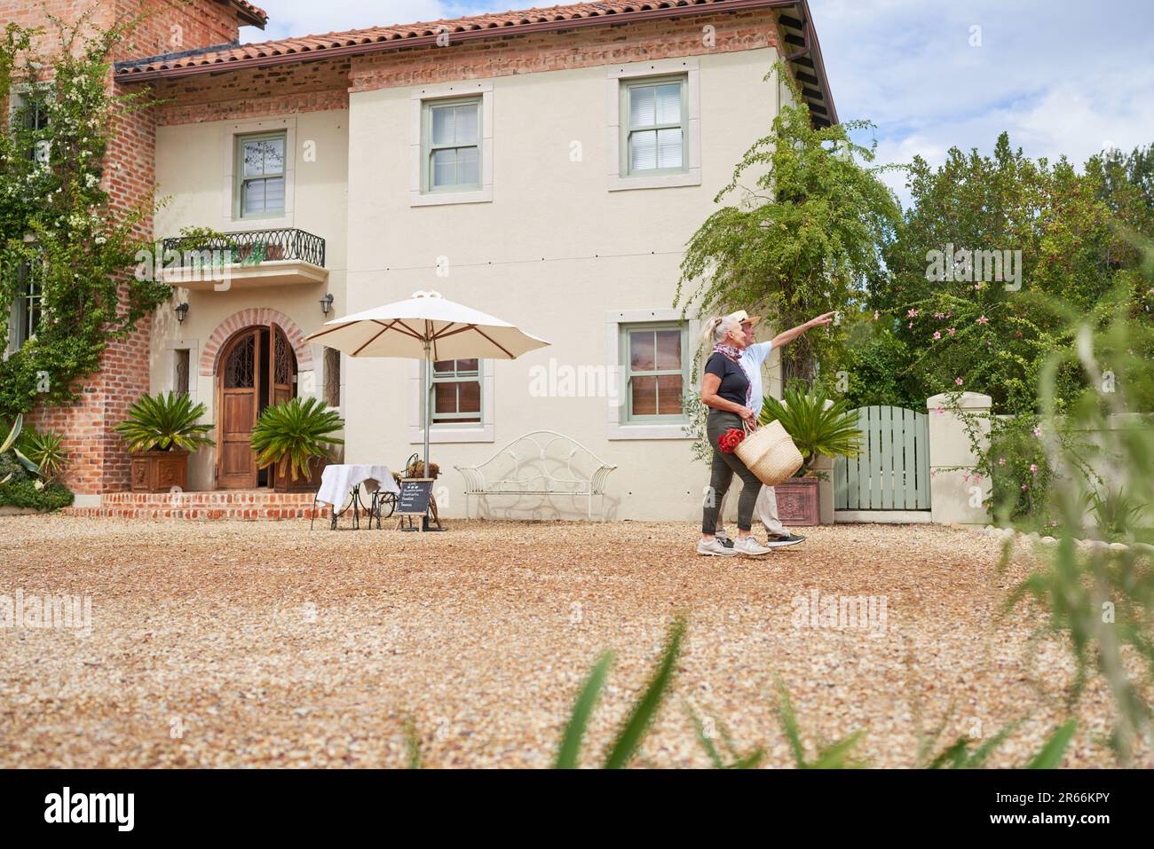 Couple senior parlant à l'extérieur de la villa ensoleillée d'été Banque D'Images