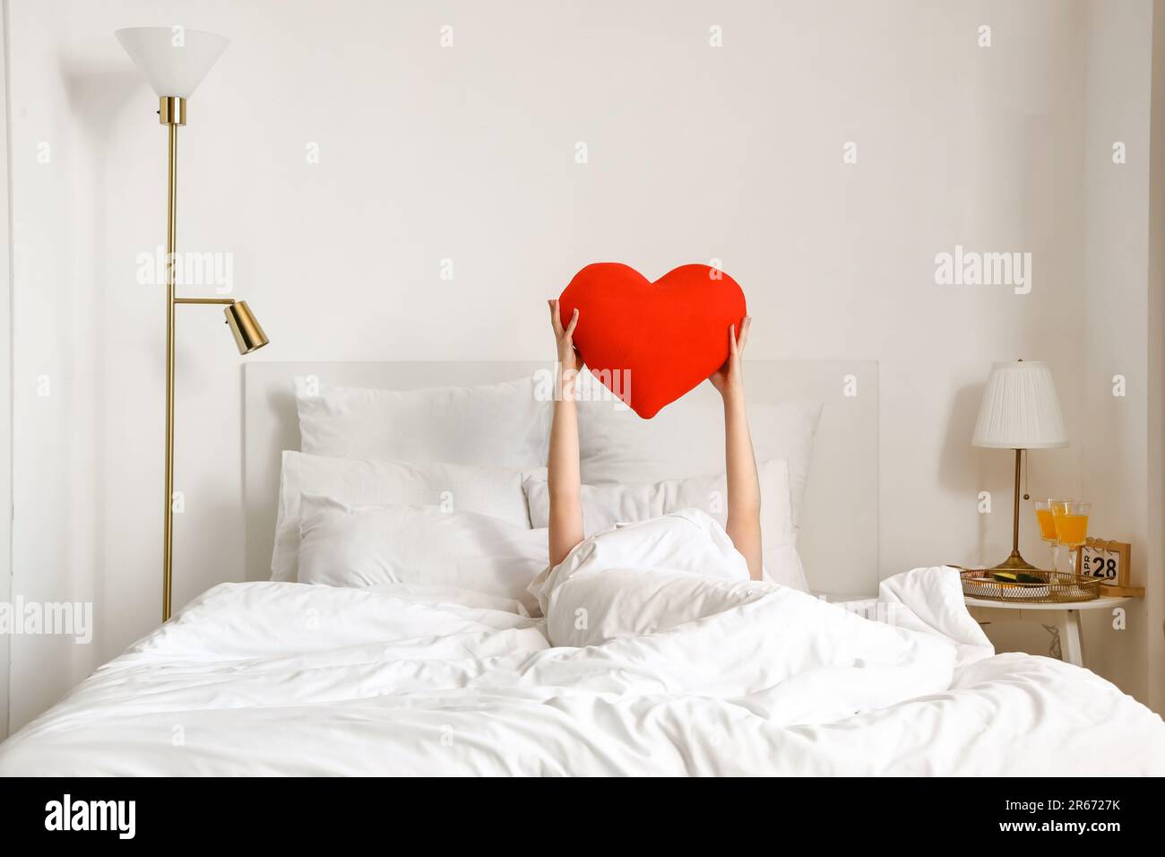 Matin de la jeune femme avec un oreiller en forme de coeur dans le lit  Photo Stock - Alamy