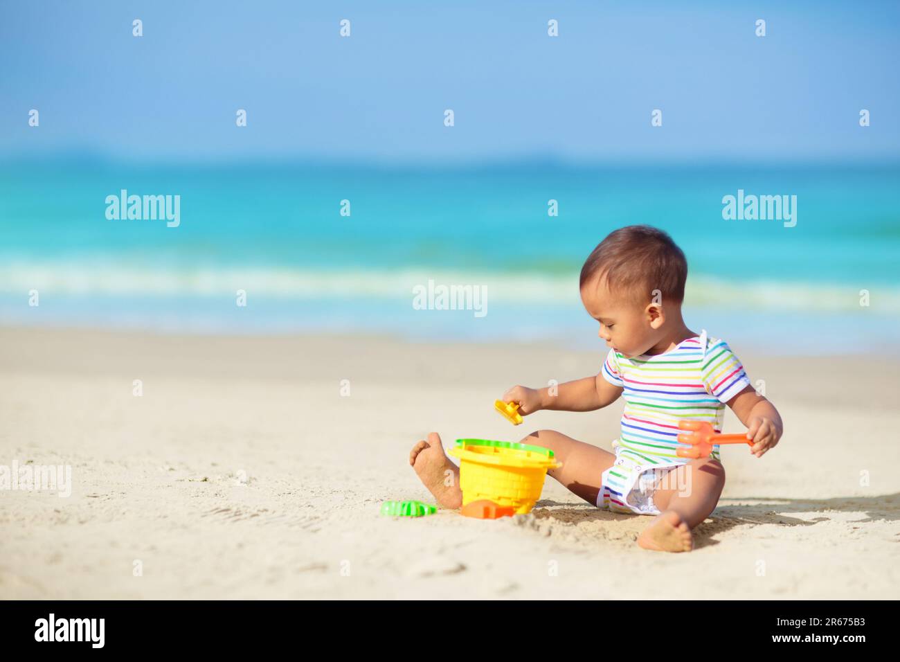 Bébé jouant sur la plage tropicale. Les enfants jouent en mer pendant les vacances d'été en famille. Jouets de sable et d'eau, protection solaire pour les jeunes enfants. Banque D'Images