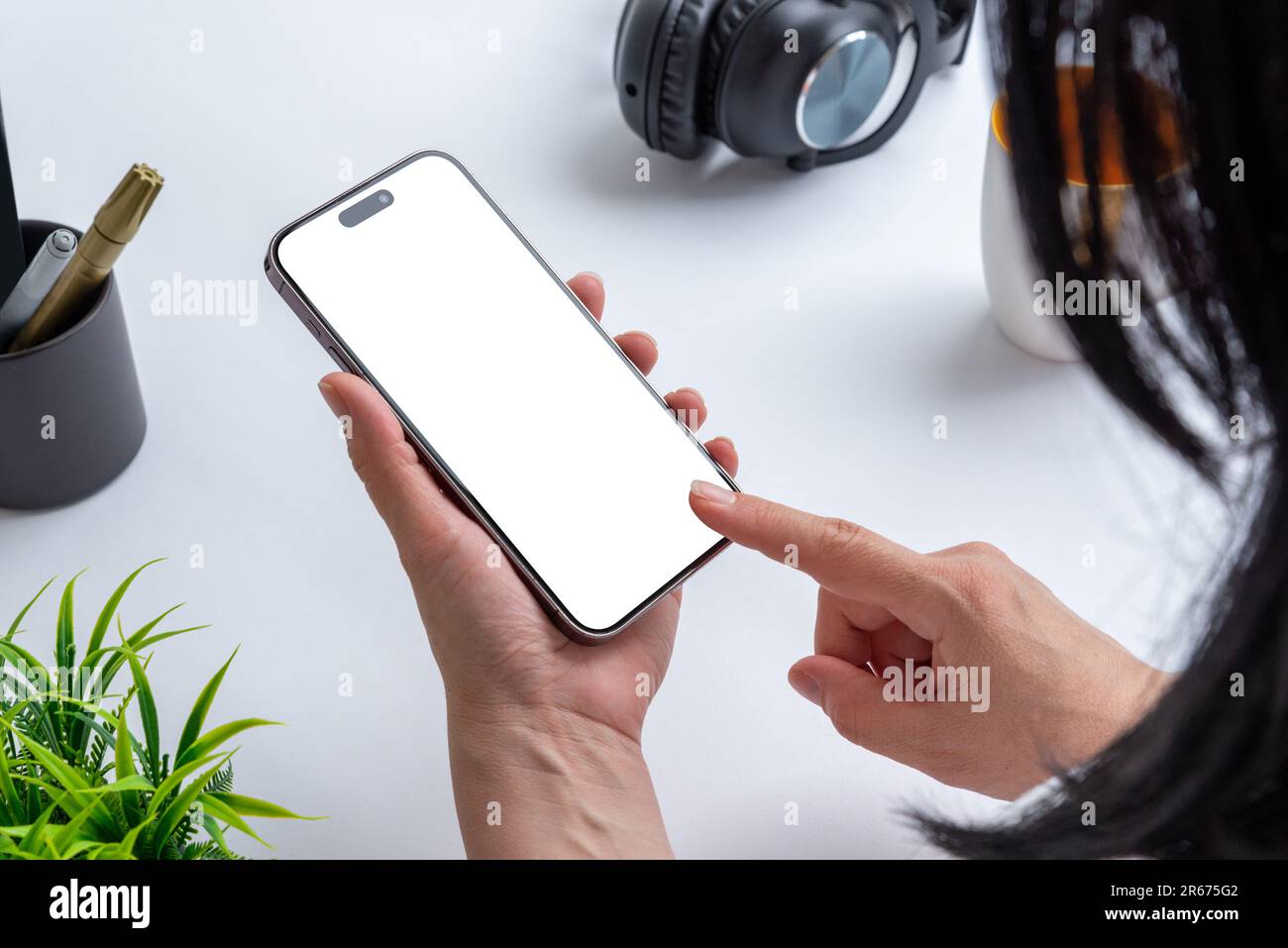 Une femme tient un téléphone avec un écran isolé pour la présentation d'applications, symbolisant la connectivité professionnelle moderne dans un bureau Banque D'Images