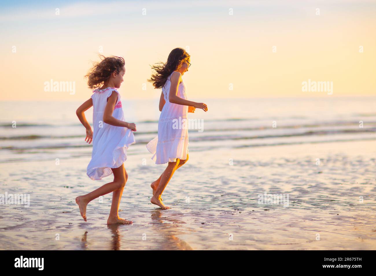 Enfant jouant sur la plage de l'océan. Les enfants sautent dans les vagues au coucher du soleil. Vacances en mer pour la famille. Petit garçon et fille courir sur l'île exotique pendant les vacances d'été Banque D'Images