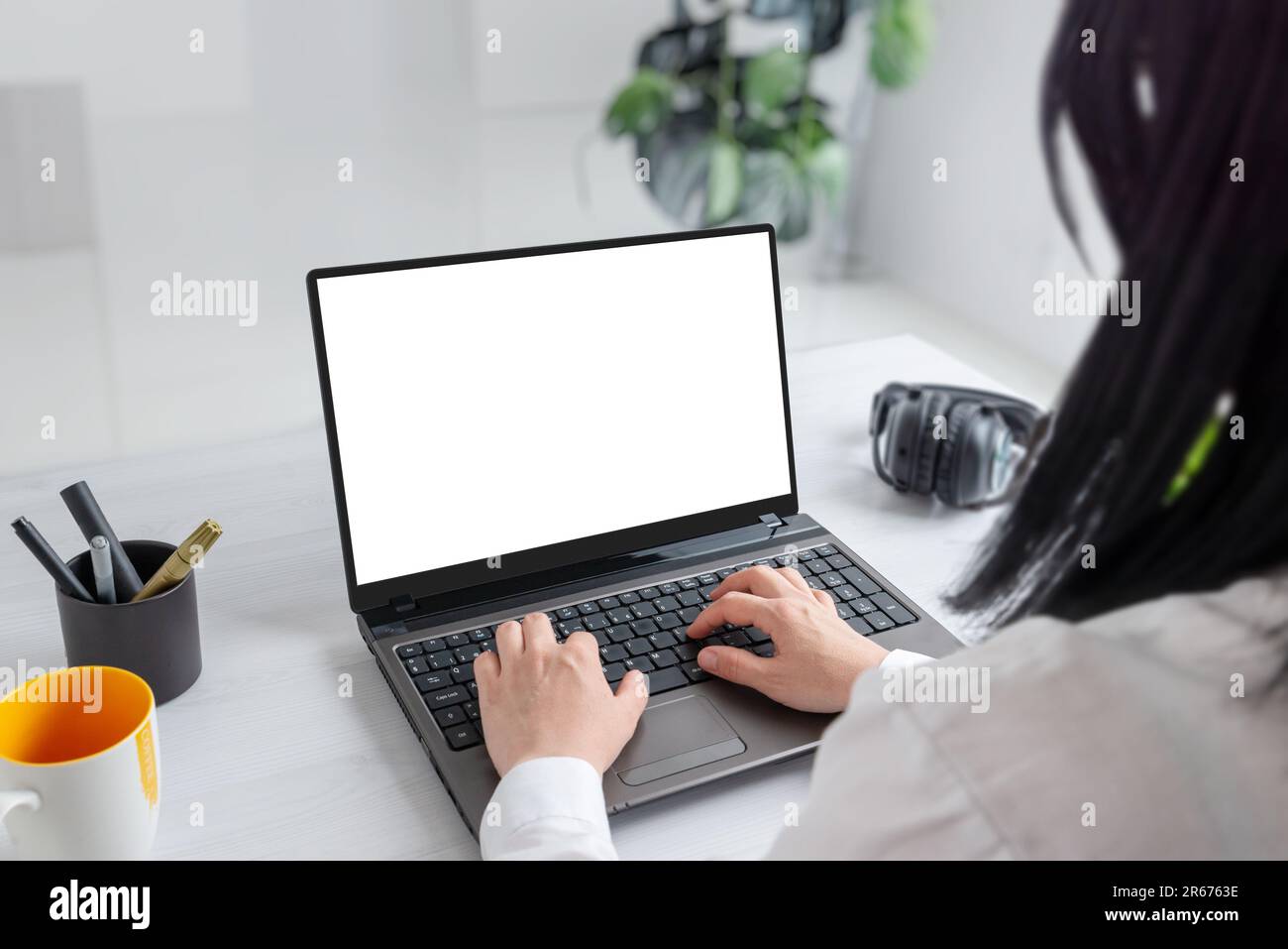 Elle s'est immergée dans ses tâches sur un ordinateur portable avec un écran isolé pour la maquette. Bureau professionnel Banque D'Images