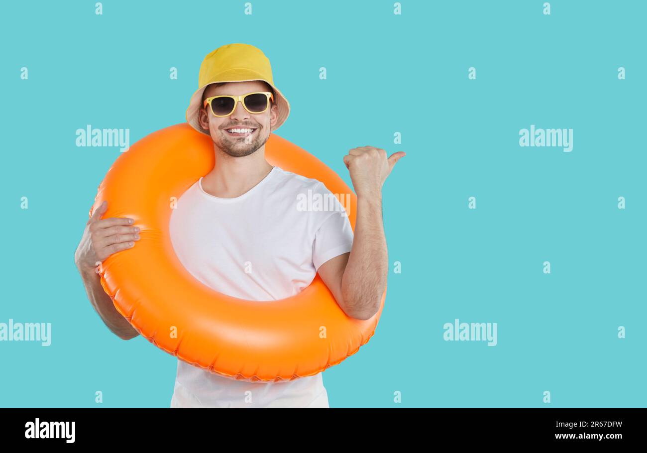 Homme gai avec cercle gonflable pour nager sur le cou montre l'espace de copie sur fond bleu clair. Banque D'Images