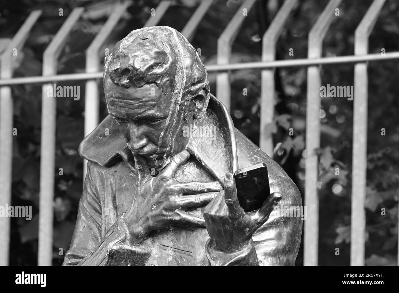 Gros plan d'une statue en bronze d'un homme tenant un smartphone en noir et blanc Banque D'Images