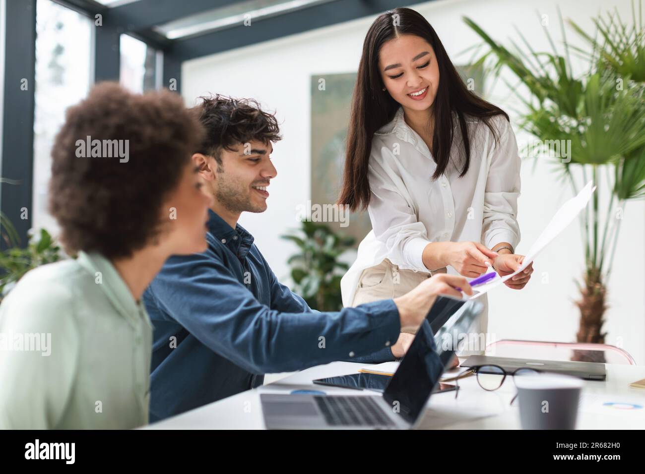 Femme coréenne présentant des papiers à l'équipe multiculturelle de l'intérieur de bureau Banque D'Images
