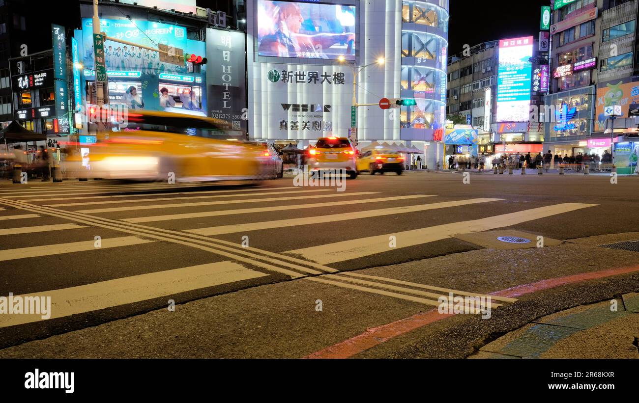 Scène nocturne, circulation, piétons, et allumé des panneaux publicitaires et d'affaires au coin de Chengdu Road et Hanzhong Street; Taipei, Taiwan. Banque D'Images