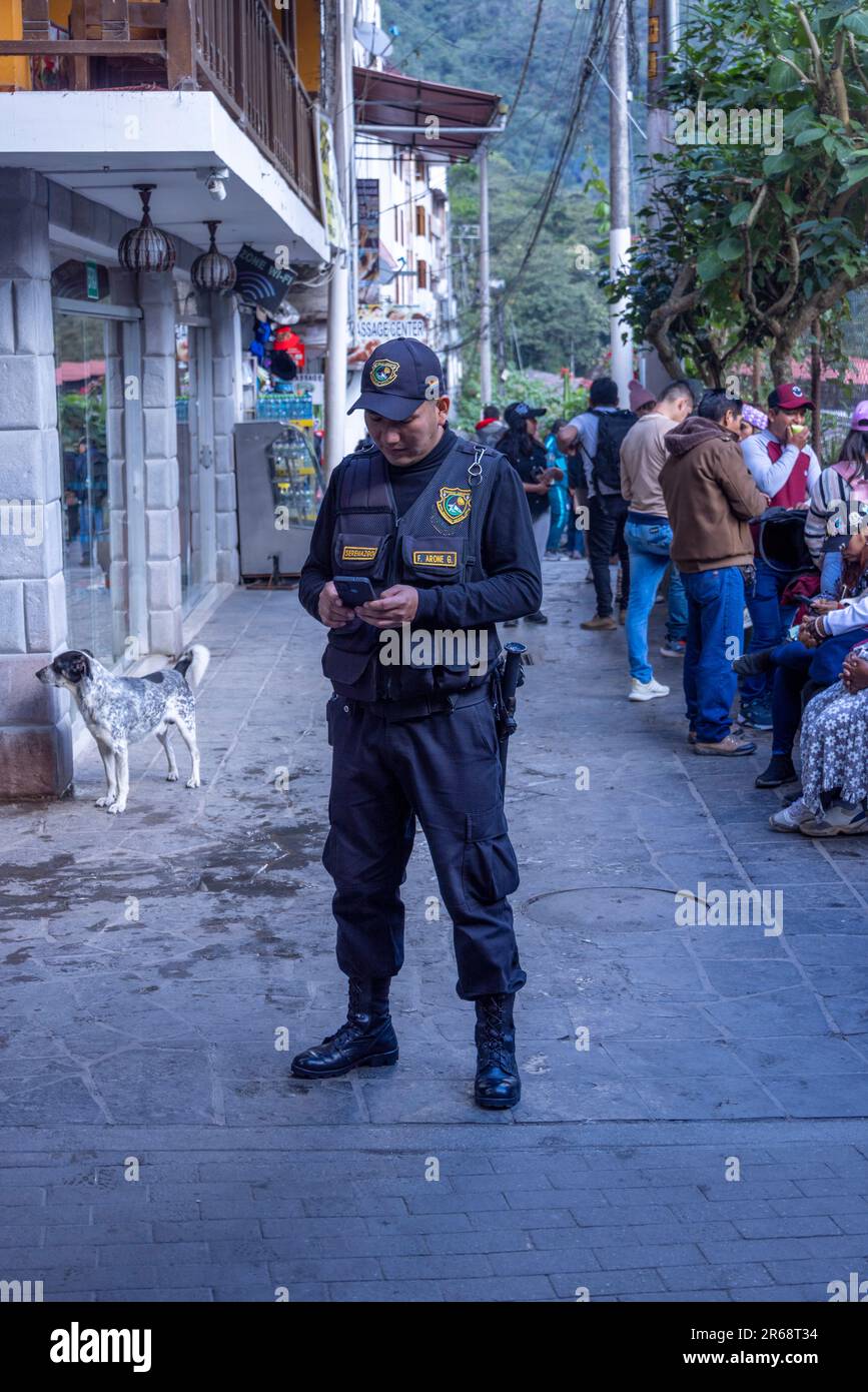 Policier sur téléphone portable, Agua Calientes, Pérou Banque D'Images