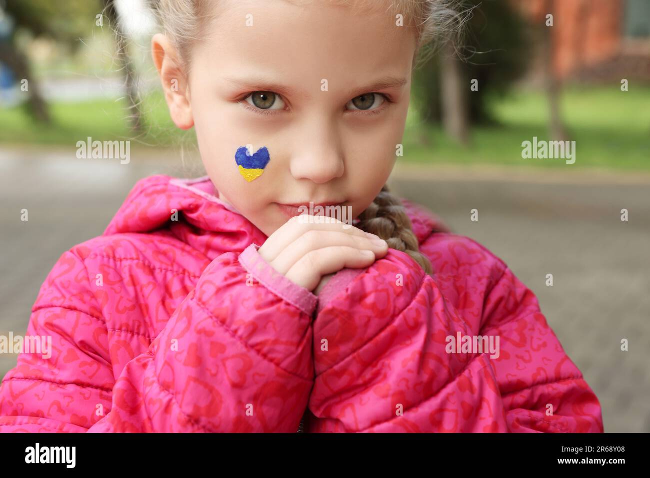 Petite fille avec dessin de drapeau ukrainien sur le visage en forme de coeur à l'extérieur, gros plan Banque D'Images