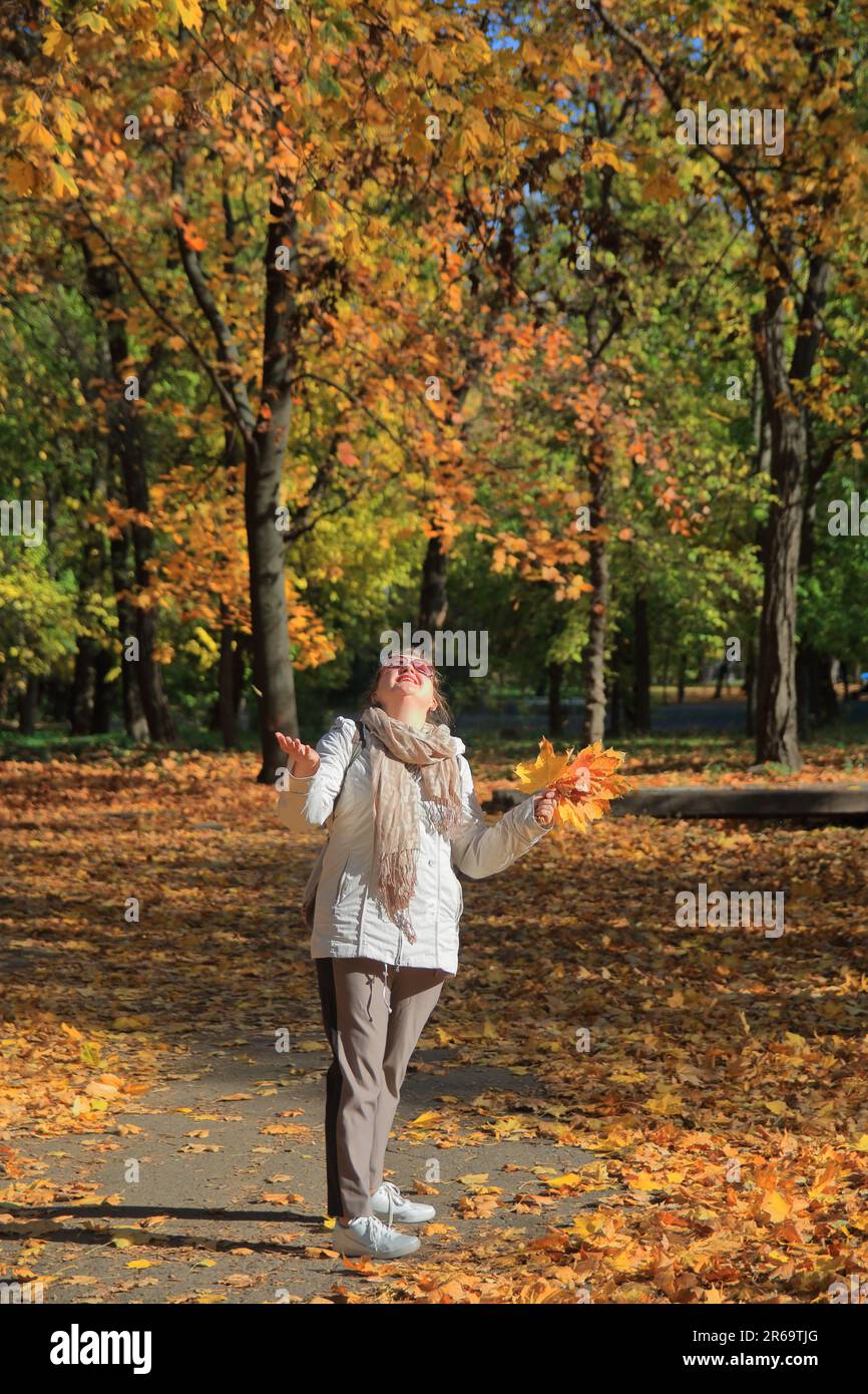 La photo a été prise dans le parc d'Odessa appelé le jardin de Dyukovsky. Dans la photo, une fille attrape joyeusement des feuilles jaunes tombant d'un arbre en automne Banque D'Images