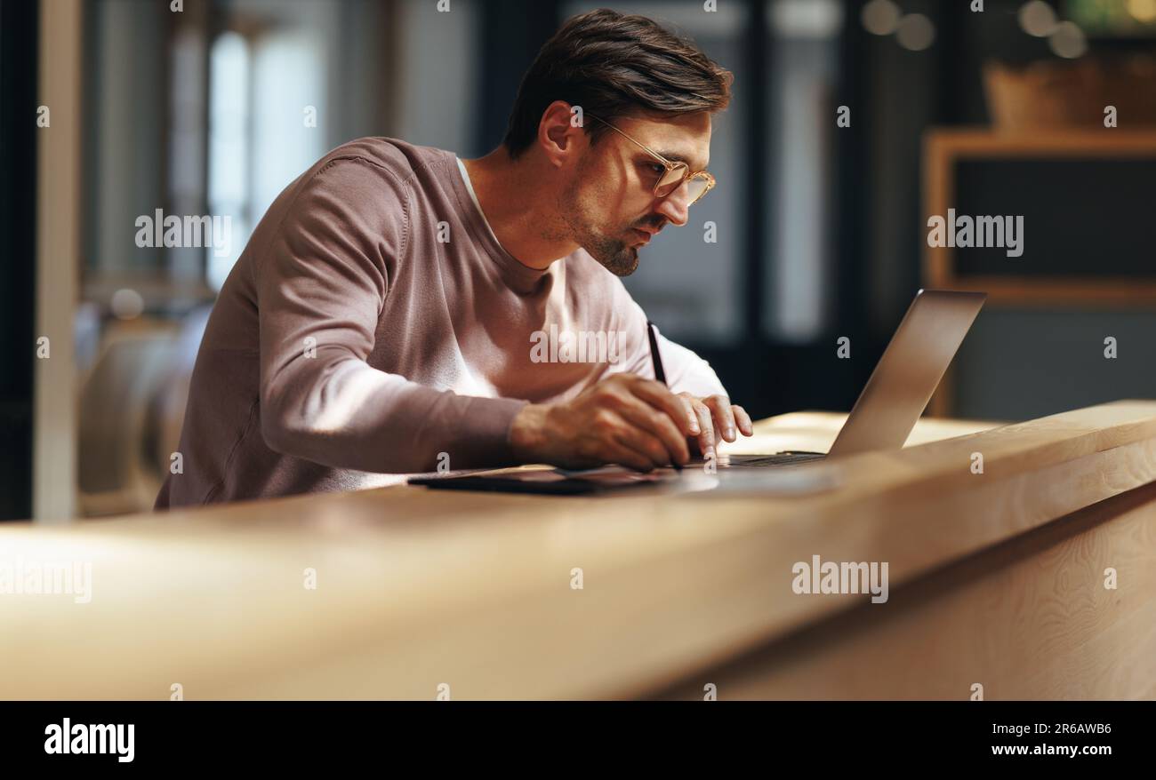 Graphiste spécialisé dessinant sur une tablette graphique dans un café. homme d'affaires travaillant sur un design avec un ordinateur portable. Conception masculine professionnel travaillant remo Banque D'Images